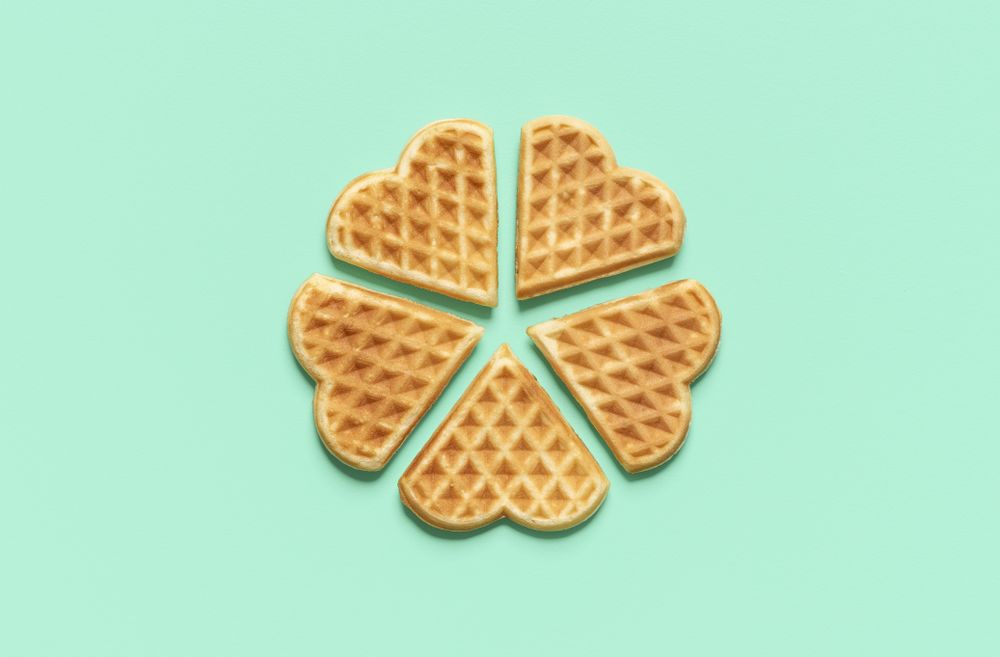 Heart shaped waffles top view on a green table