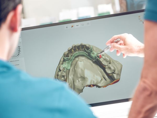 Dentist pointing at monitor with jaw model