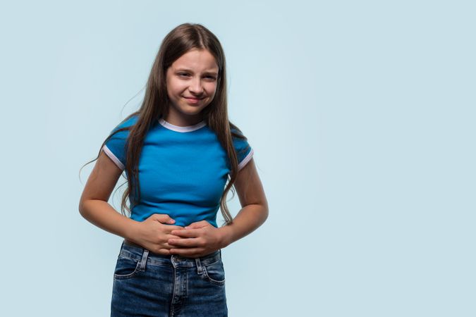 Young girl holding stomach, showing signs of abdominal discomfort