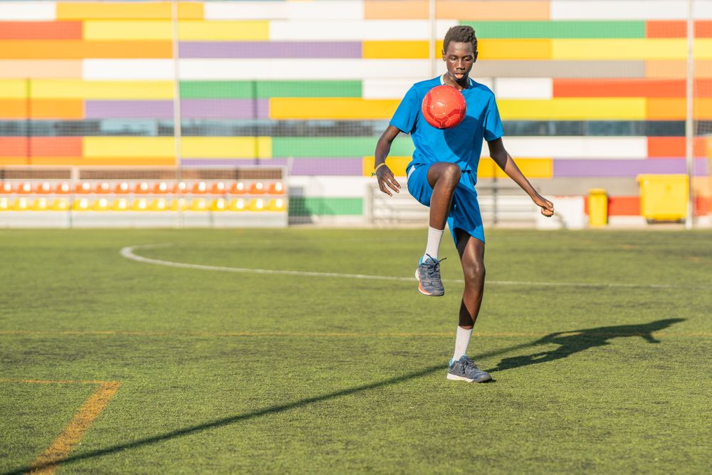 Black teenager juggling football ball