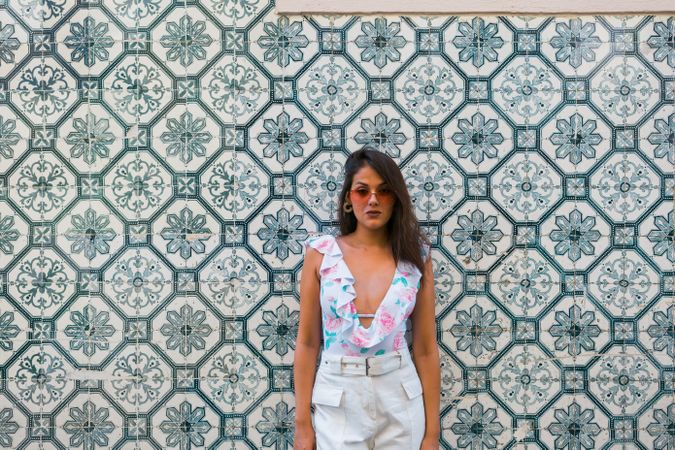 Dreamy stylish woman in sunglasses standing on city street