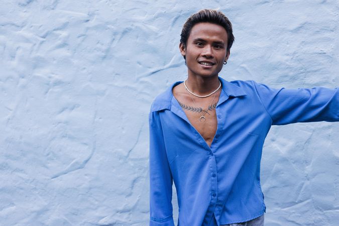 Happy Asian male in blue shirt with tattoo across his chest