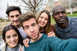 Group of friends looking down at camera and posing for selfie