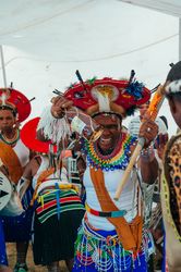 Woman with beer and traditional Zulu wedding attire laughs and smiles at camera