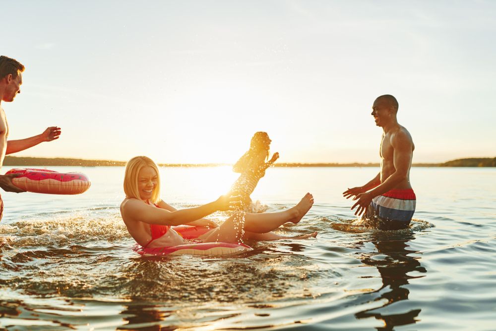 Multi-ethnic group of friends splashing in the lake at sunset