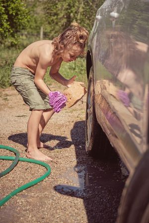 Little boy washing car on sunny day