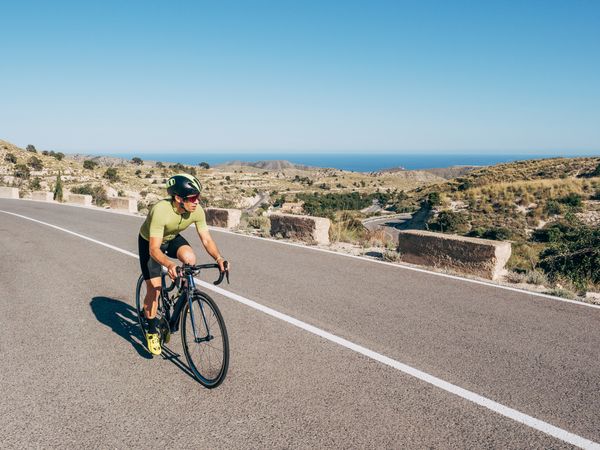 healthy man riding a bicycle on a mountain road in a sunny day