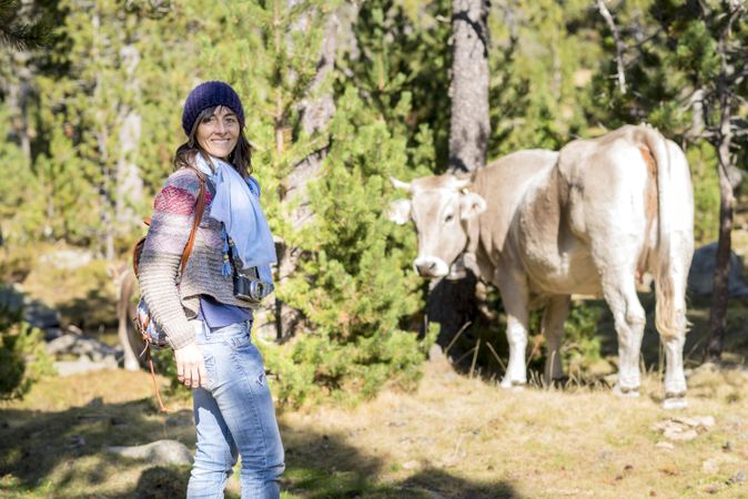 Smiling woman in forest with cow