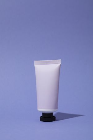 Lilac tube with cream on purple background