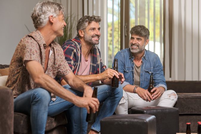 Happy friends sitting on sofa while watching TV together