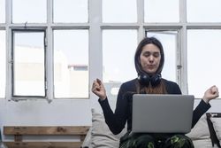 Beautiful Woman sitting on sofa with arms up in front of laptop