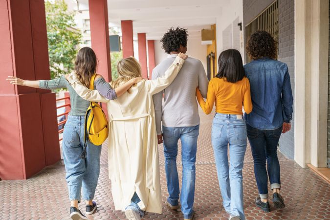 Backs of multi-ethnic friends walking down the street