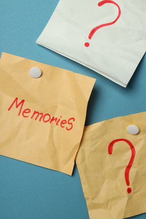 Vertical composition of pinned post it notes with the word “memories” on blue board