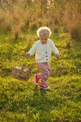Content girl with basket strolling on lush lawn