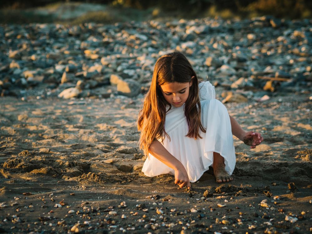 Adorable girl playing with sand on beach