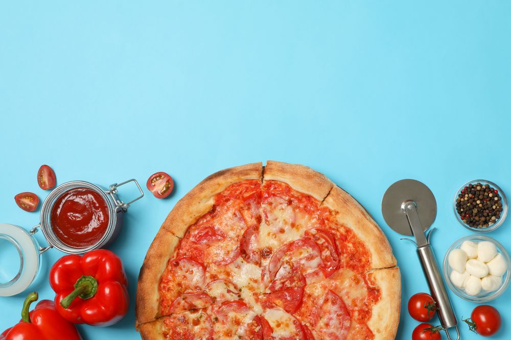 Tasty pizza and ingredients on blue background