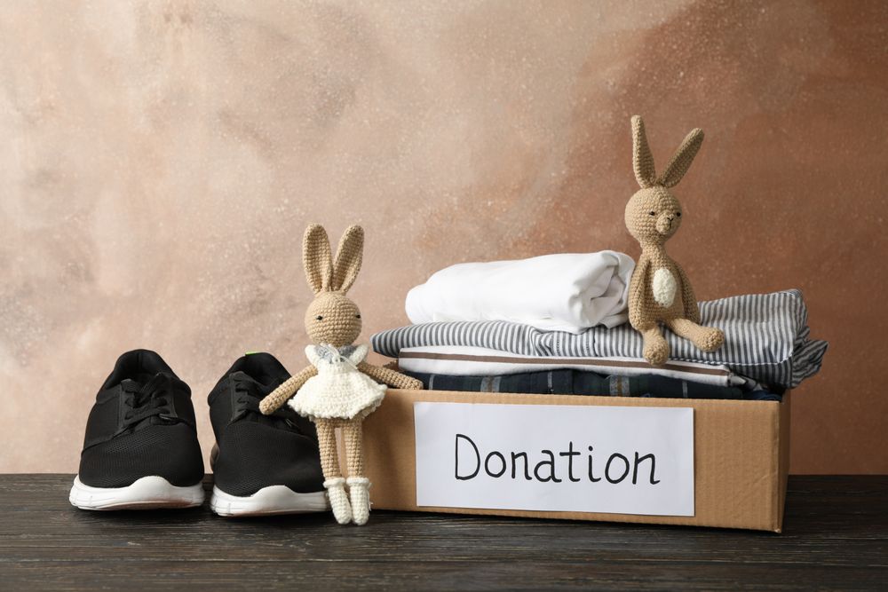 Donation box with clothes and toys on wooden table