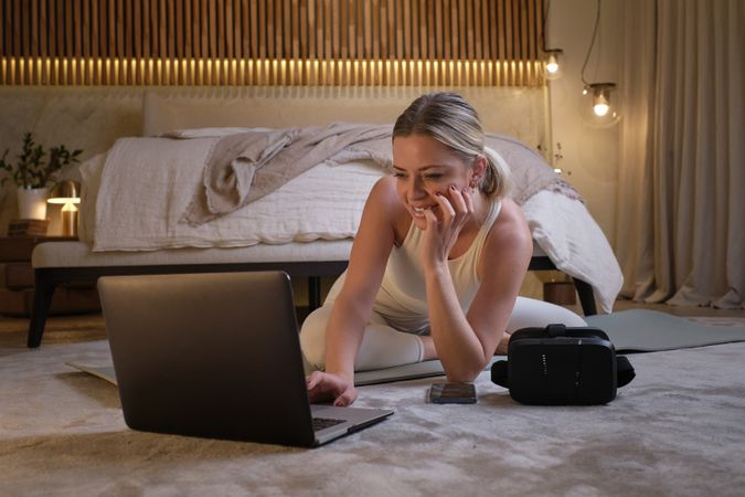 Sportswoman looking for online yoga tutorial on laptop in bedroo