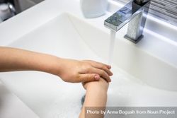 Person rinsing hands at sink bYqmk9