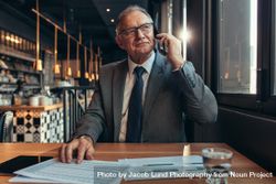 Confident businessman at coffee shop making a phone call bxygn0