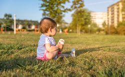 Happy baby girl playing sitting on a grass park