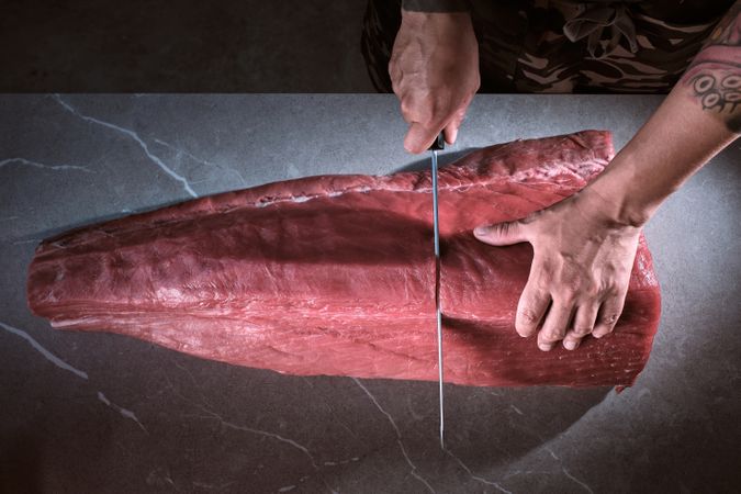 Male hands of a chef cutting a delicious loin of fresh bluefin t