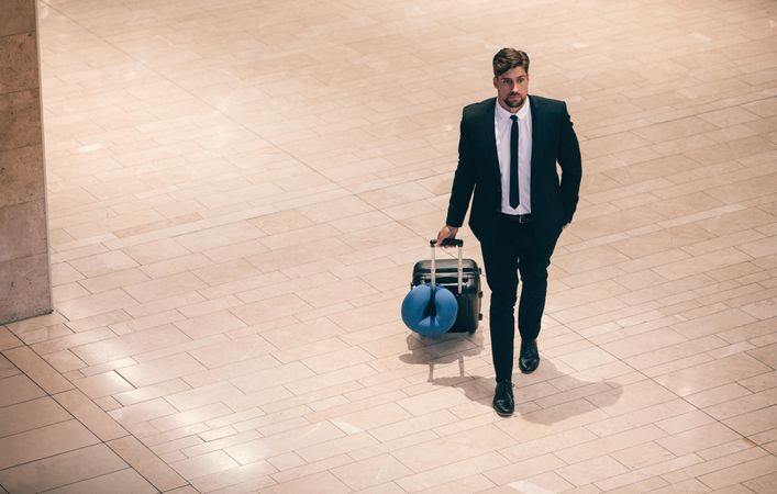 Business traveler with luggage at airport terminal