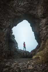 Woman standing inside rocky cave