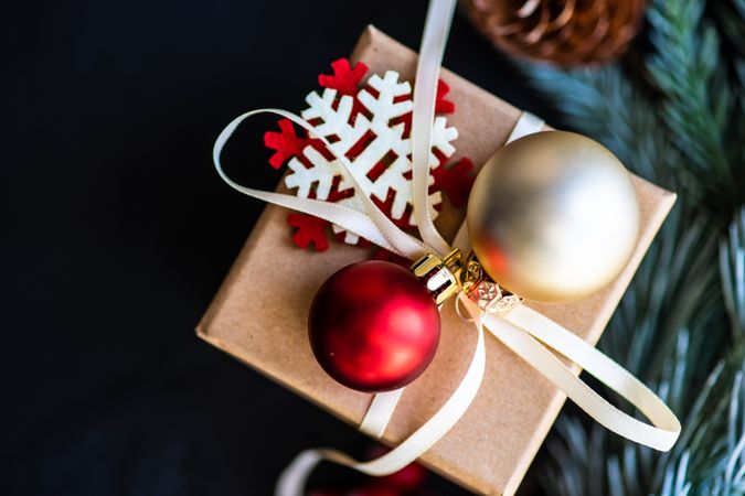 Close up of Christmas present with baubles and surrounded by pine branch