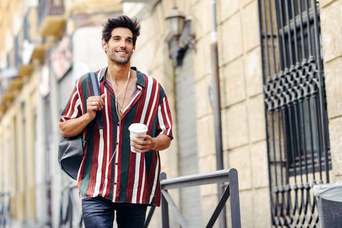 Male in striped shirt enjoying the streets of Granada, Spain with coffee