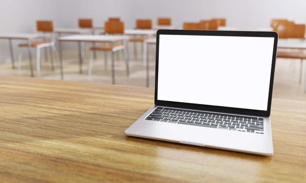 Looking at blank laptop on teacher’s desk in school