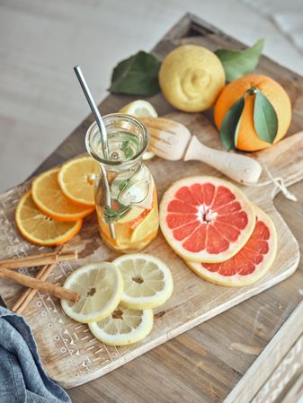 Slices of fruits and bottle of lemonade on cutting board