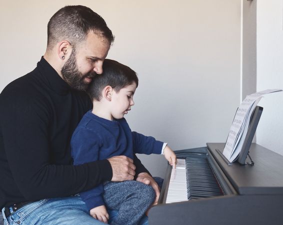 Father teaching son to play piano