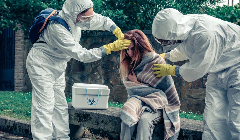 Doctors in protection suits caring for a woman