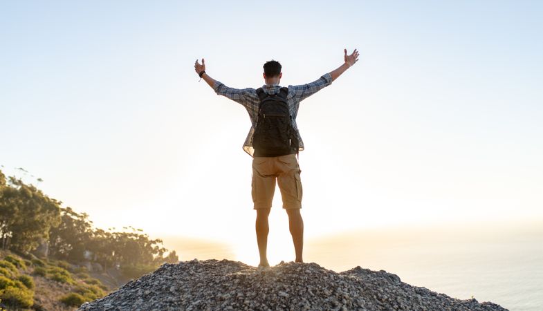 Hiker with arms outstretched on hill top