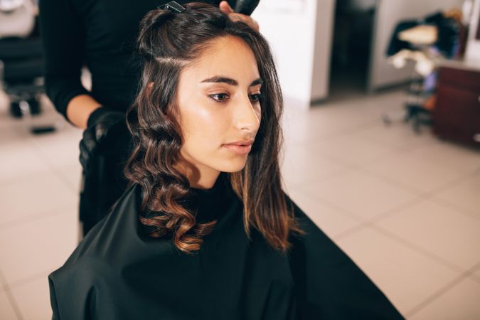 Young woman sitting in salon chair getting hair curled