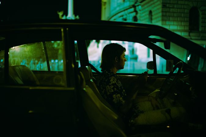 Side view of young man sitting in a car at night