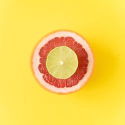 Red grapefruit and lime slice on pastel yellow background