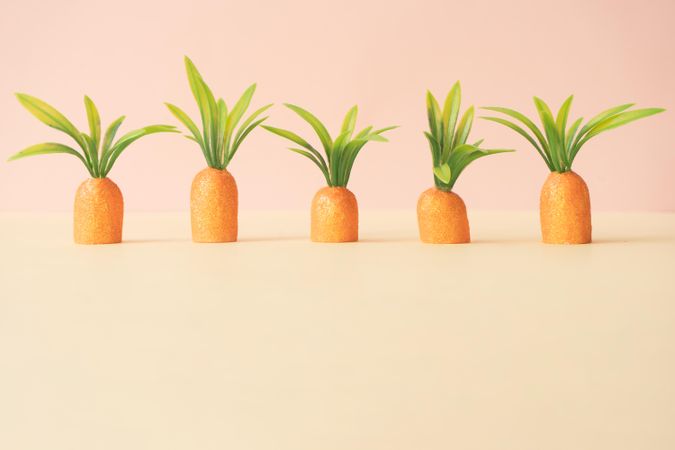 Row of carrots on pastel yellow background