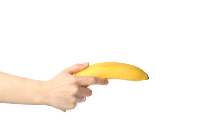 Female hand holds banana, isolated on bright background