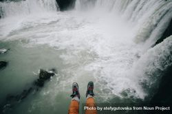 Hiker’s legs hanging over waterfall 0gPvX5