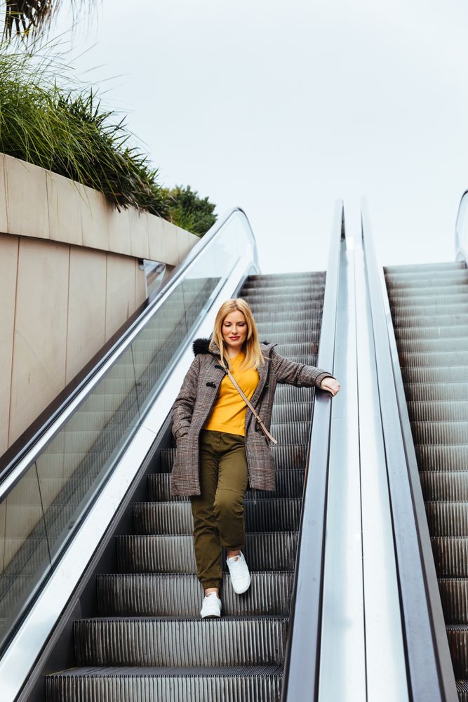 Blonde woman going down escalators