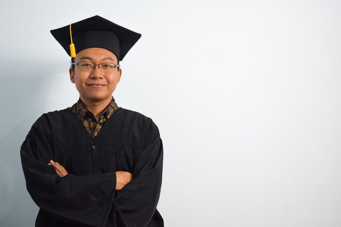 Proud male graduate in studio shoot with arms crossed