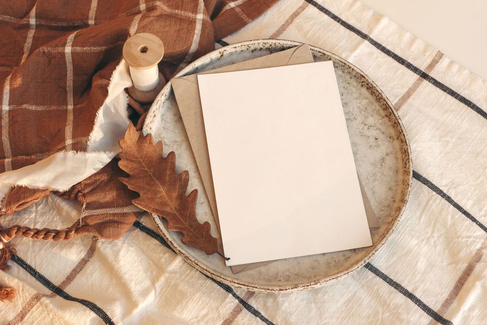 Blank card on ceramic plate on autumn themed table setting