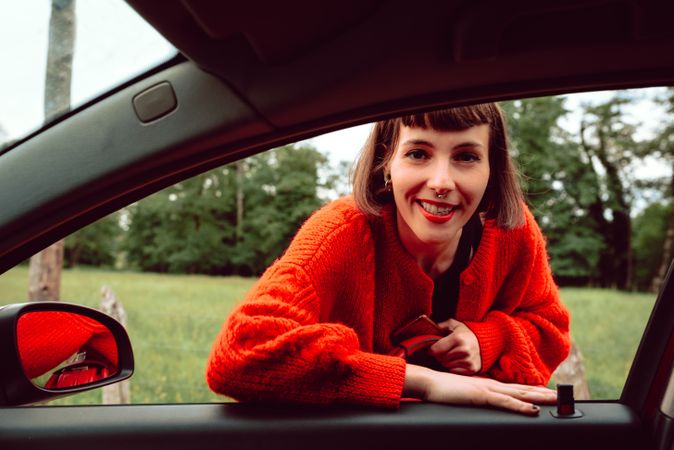 Woman putting suitcase in front window of car