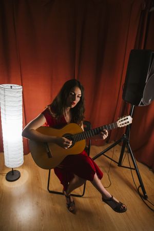 Creative woman singing and playing guitar on stage