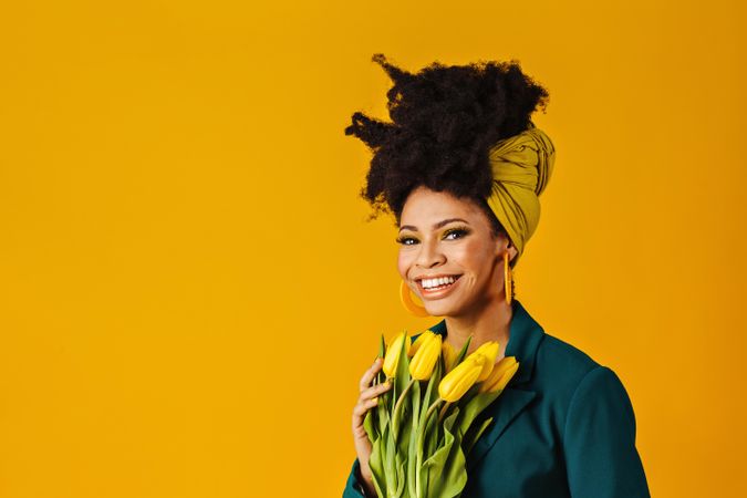 Portrait of happy Black woman with tulips, earrings and head wrap