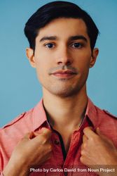 Portrait of serious Hispanic male fixing his shirt, vertical 5pwK80