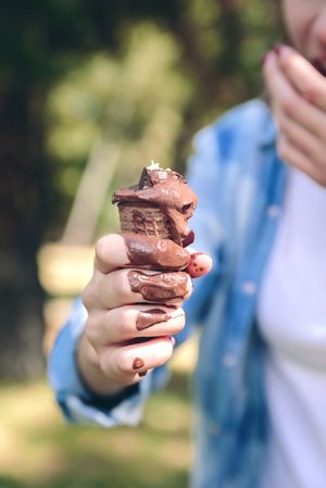 Chocolate ice cream cone melting in hand