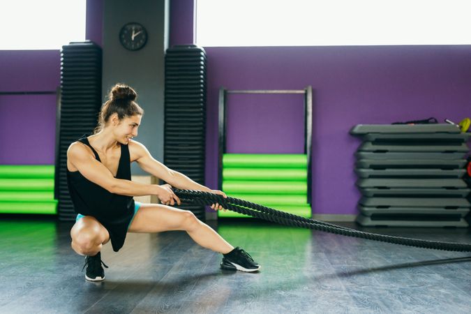 Muscular woman on ground working out with ropes